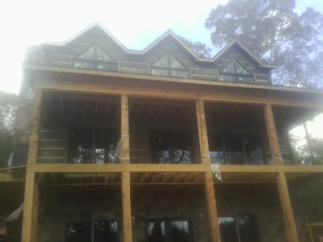 Dormers and porch framing on a large log home under construction — Roof Coating work by our crew in Whitfield