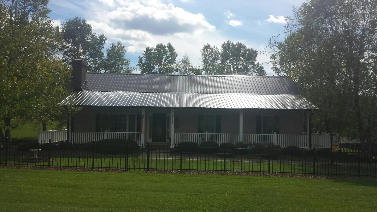 Gray metal roof on a brick ranch with a full width front porch — Gutter Guard Installation work by our crew in Whitfield