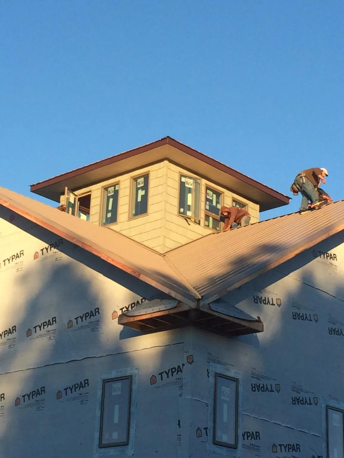 Roofers working around a rooftop cupola on a new metal roof at sunset — Roof Waterproofing in Whitfield by Roofing Brothers